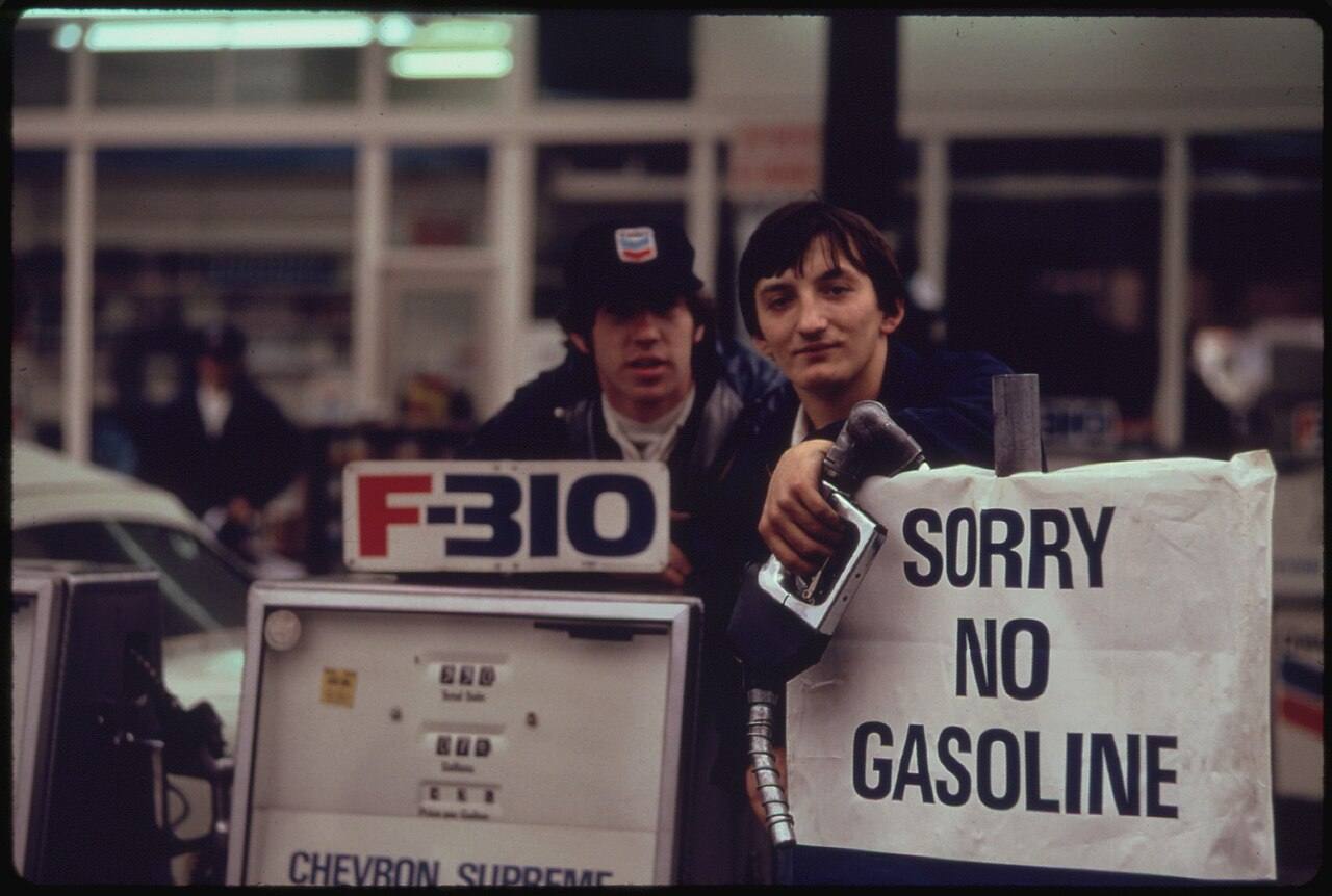 Gas station attendants peer over their "out of gas" sign in Portland