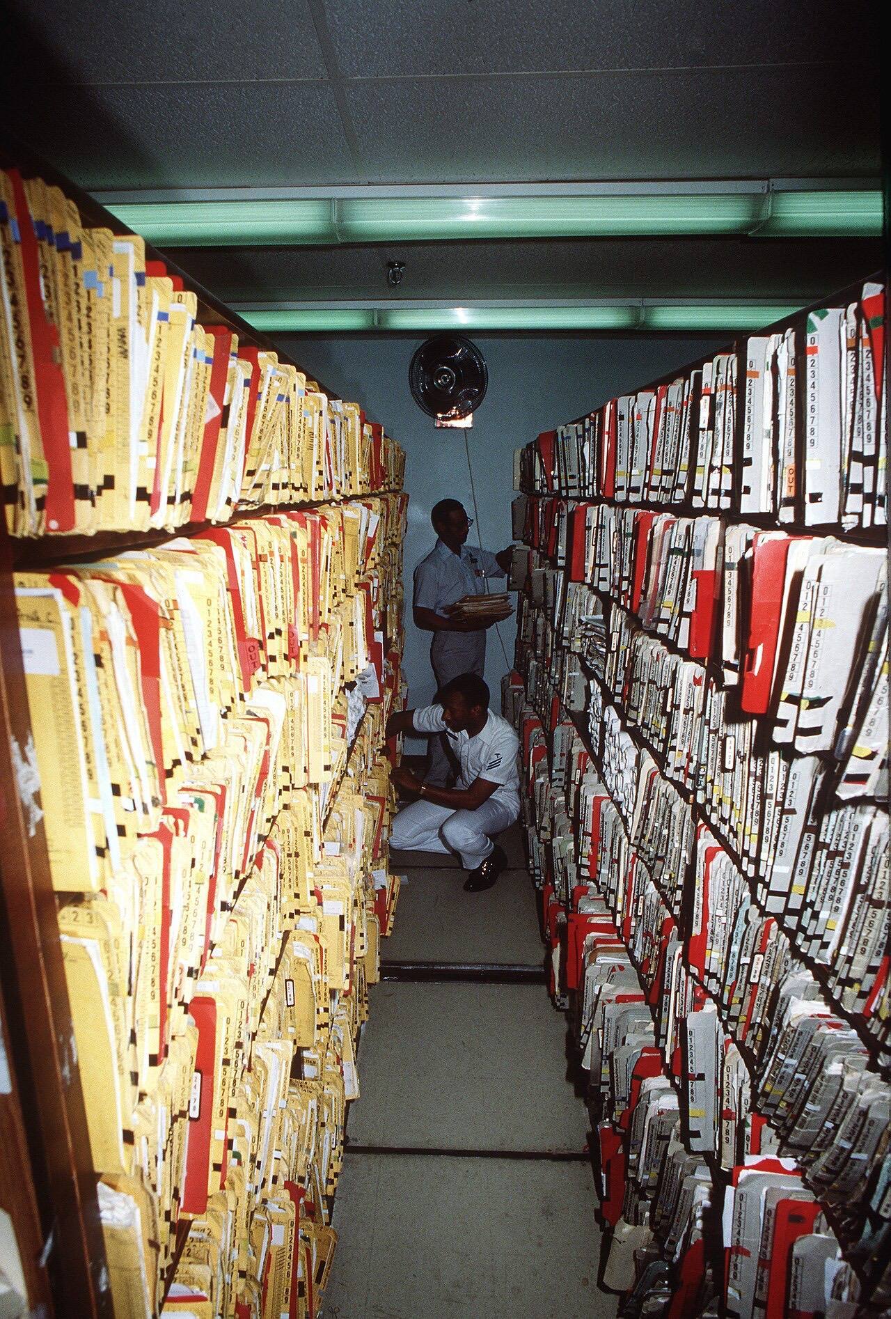 A hospital corpsman and a civilian employee file medical records at the naval hospital