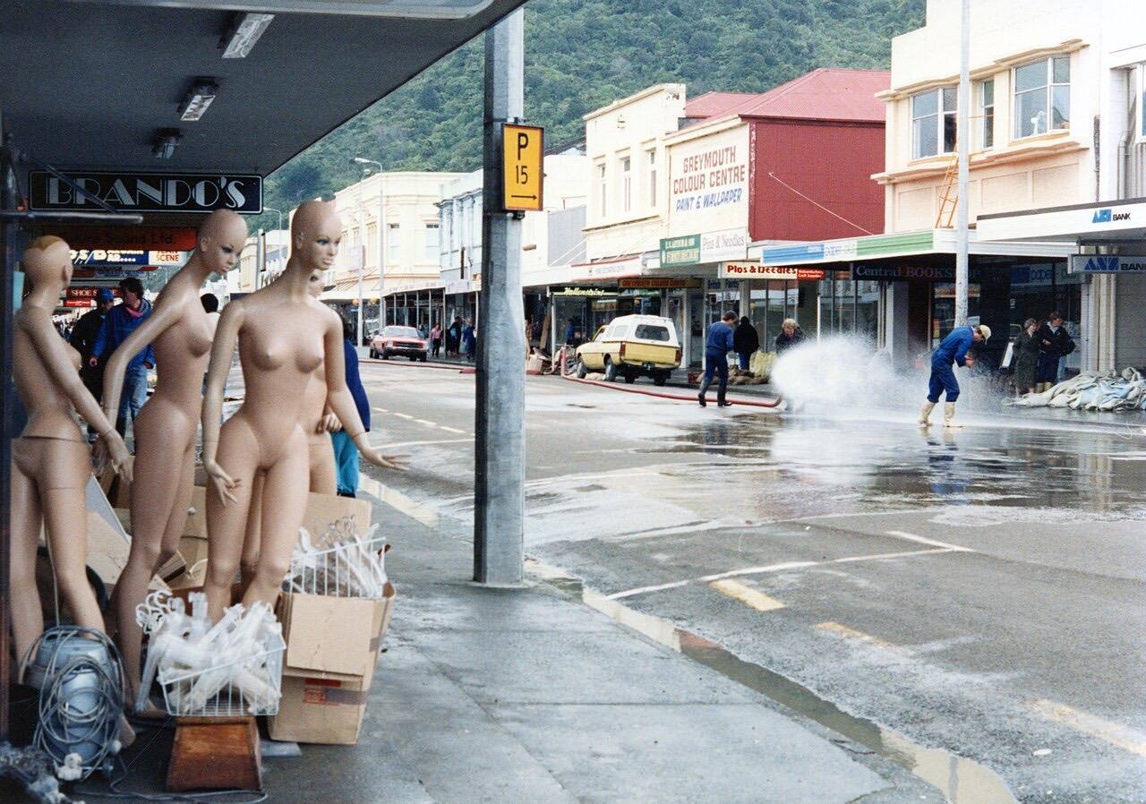 Workers hosing down Mackay Street after the flood. Mannequins, clothing hangers and other materials from shops line the footpaths.