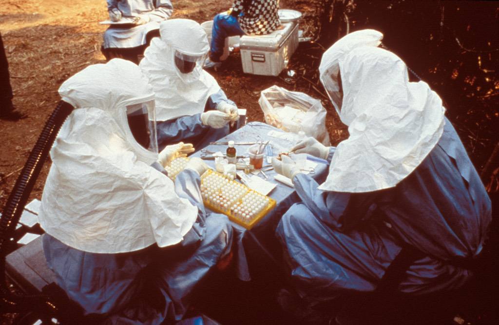 This 1995 photograph shows scientist with personal protective equipment (PPE) testing samples from animals collected in Zaire for the Ebola virus.