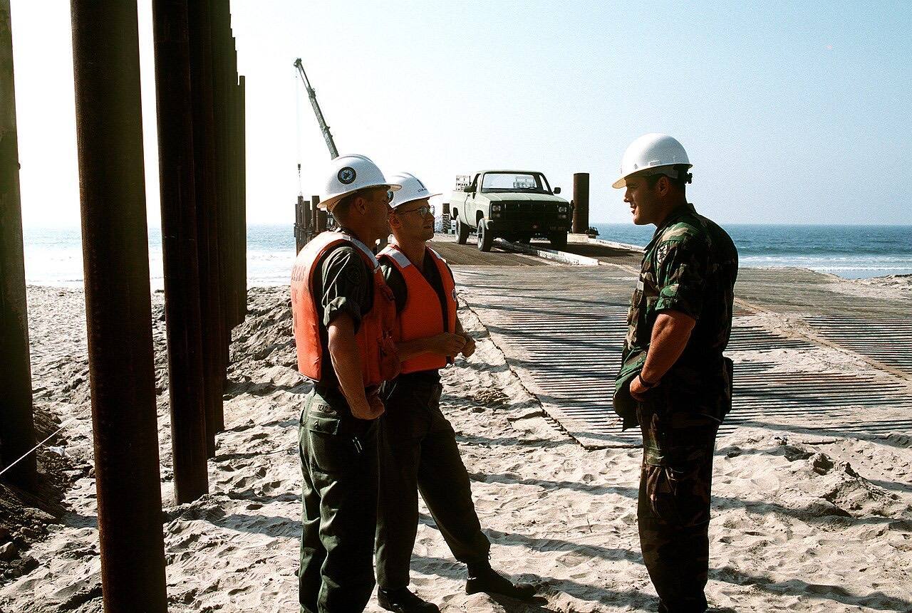 U.S. Army's 1ST LT. Albert E. Quaye (right) of the 497th Engineering Company talks with LT. j.g. Michael A. Read (left) and LT. j.g. Donald D. Naiser of the Nav