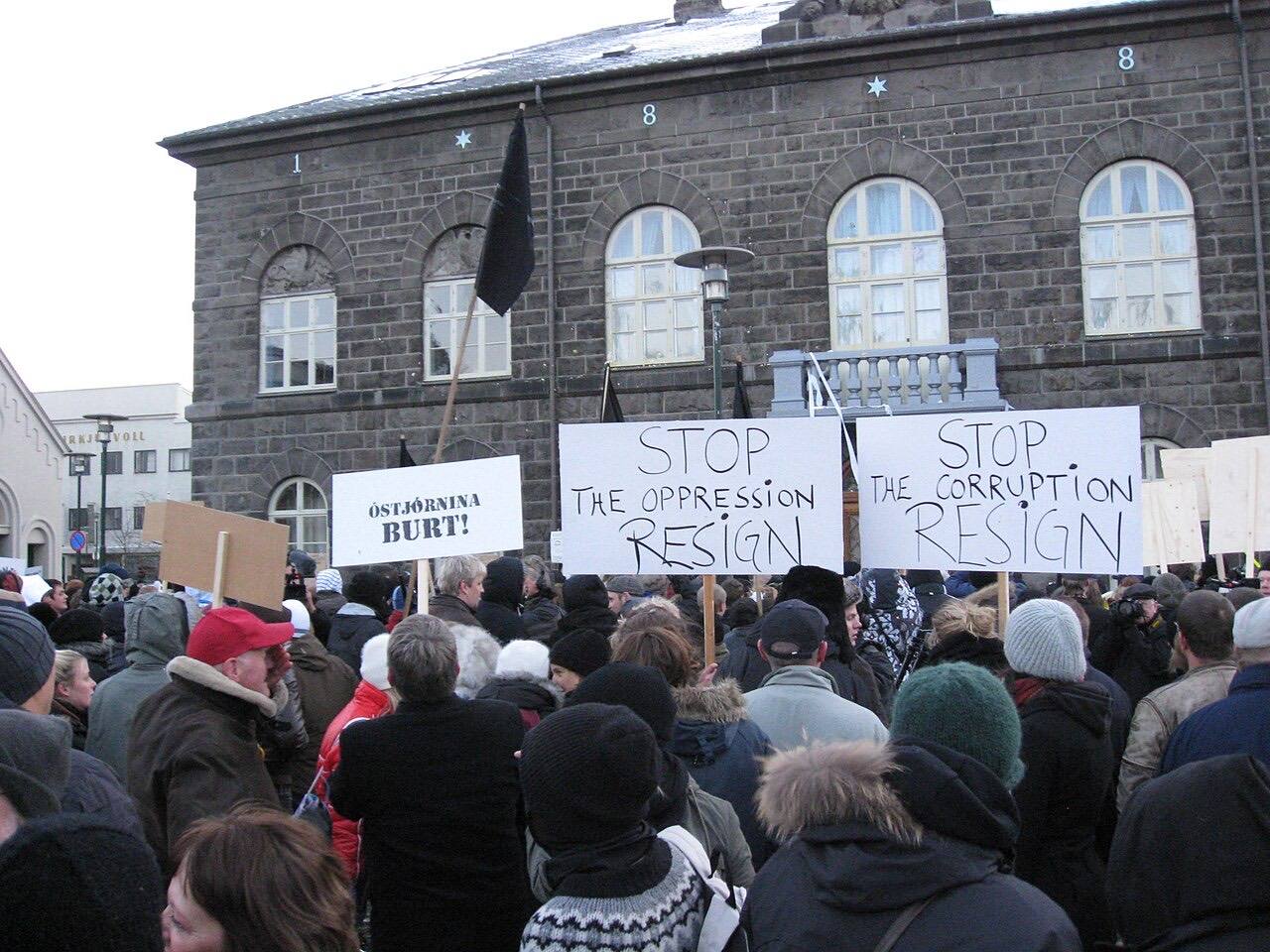 Protests on Austurvöllur because of the Icelandic economic crisis. Some protesters are waving black flags, some have signs in English.