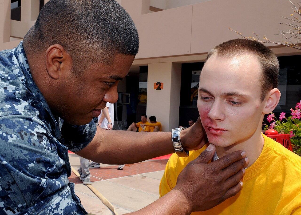 US Navy 100518-N-6326B-032 Hospital Corpsman 1st Class Ricardo A. Blake assesses facial burns and abrasions on the face of Hospital Corpsman Seaman Patrick T.