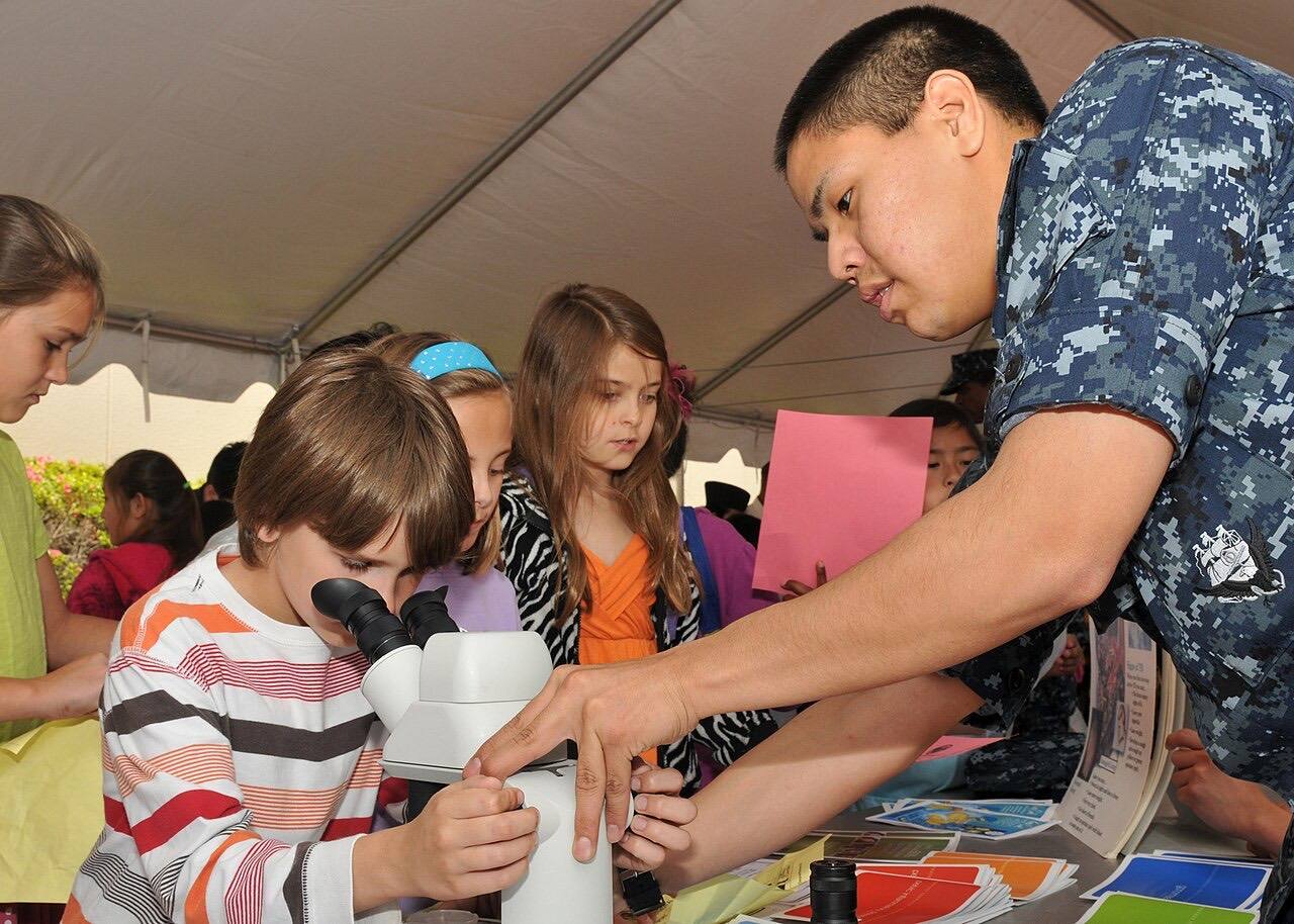 US Navy 100527-N-2013O-003 Hospital Corpsman 3rd Class Brandon Sheaky-Ward, from Anchorag, Ak., helps a girl examine a mosquito under a microscope