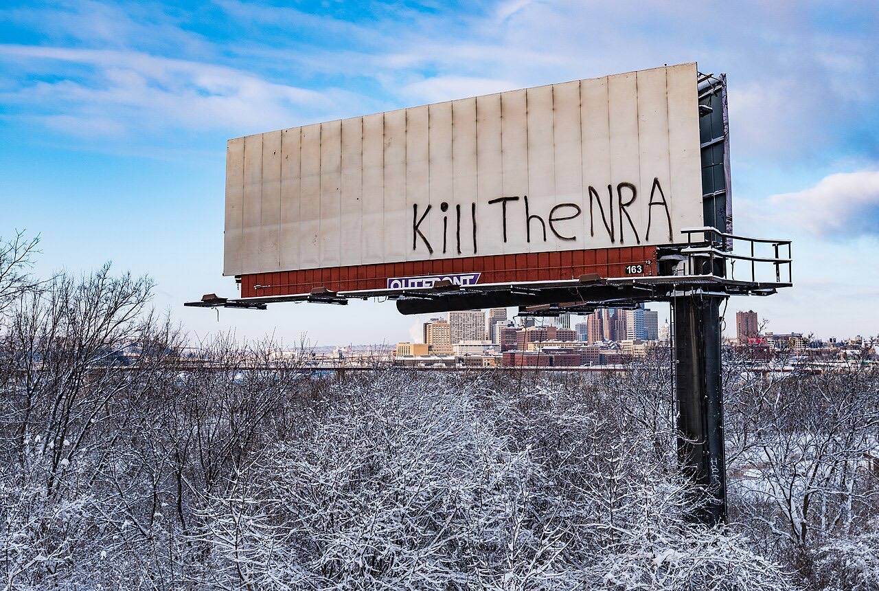 A billboard in front of the Saint Paul, Minnesota skyline vandalized with "Kill The NRA" (National Rifle Association).