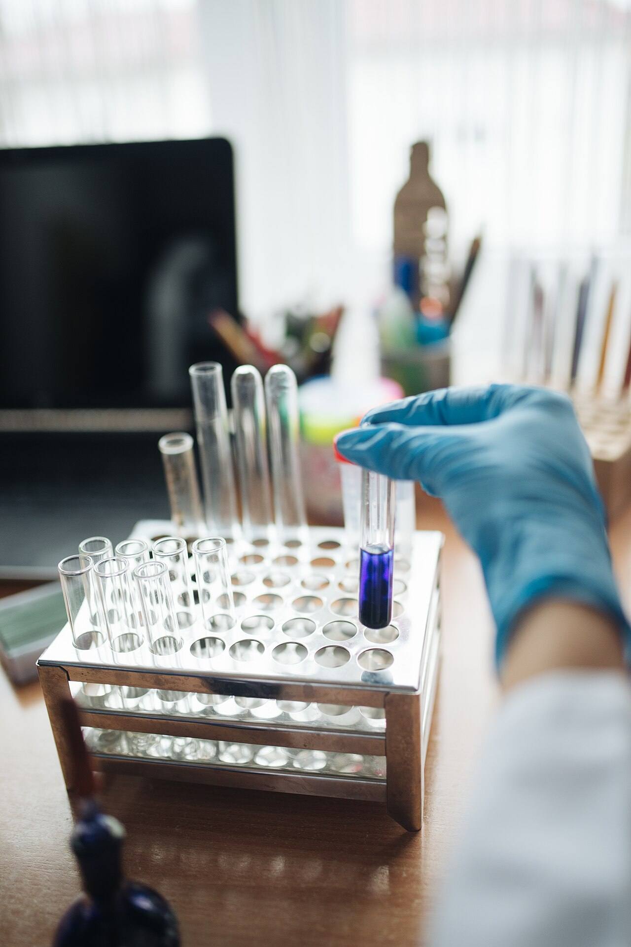 Close-up of a lab technitian putting a test tube with ink and water solution on a rack